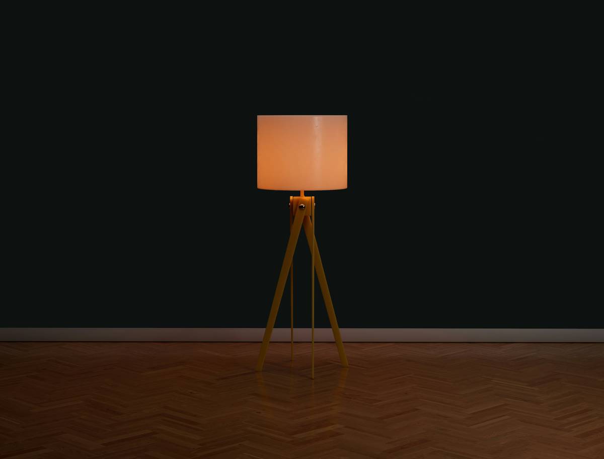 A cozy living room using interior lighting for mood enhancement with warm floor lamps, wall sconces, and dimmed overhead lights